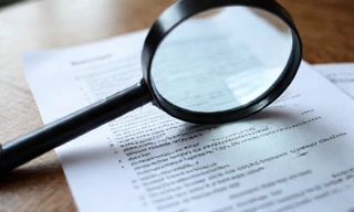 A magnifying glass over a document with small text, symbolizing transparency and attention to detail.
